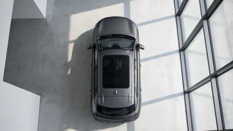 Vista cenital de un BYD Atto 3 en un concesionario luminoso, con luz natural de un gran ventanal sobre hormigón pulido